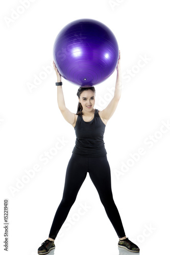 Young woman lifting fitness ball