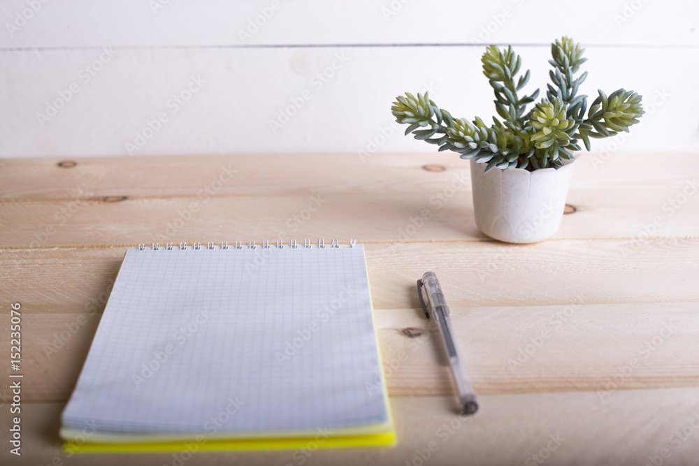 Opened notebook with a tiny flower on wooden table. Top view. Writing concept. Opened notebook with a tiny flower on wooden table. Top view. Writing concept.