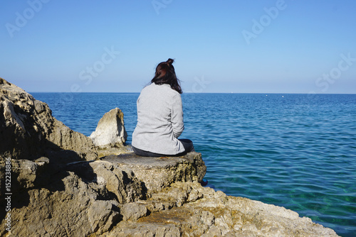 Asian woman stitting on the rock with adriatic sea background
