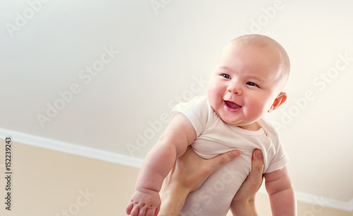 Happy infant baby girl being held up in the air
