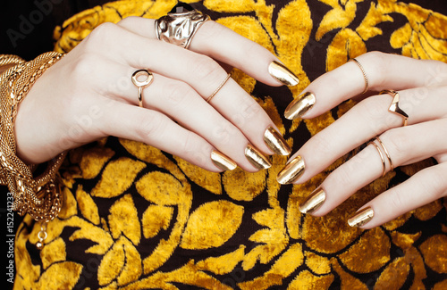 woman hands with golden manicure lot of jewelry on fancy dress close up photo