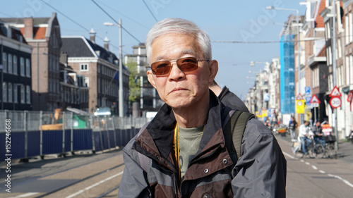 Canvas Print Asian senior man take a solo trip to Amsterdam waiting for tram transportation