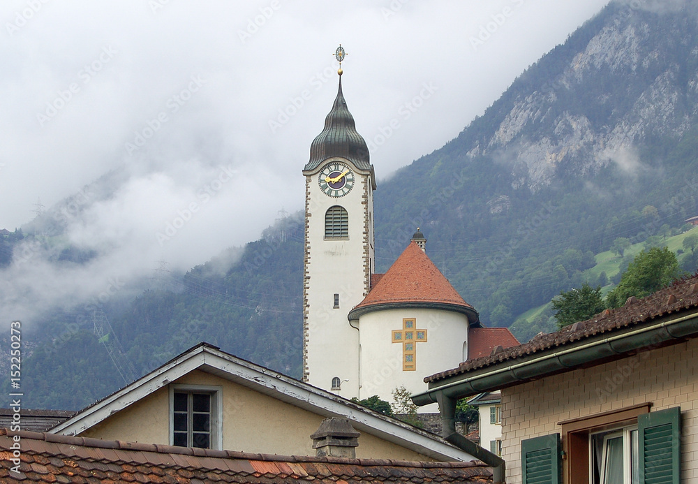 Church of Fluelen in front of foggy mountain ridges at Lake Luzern, Switzerland