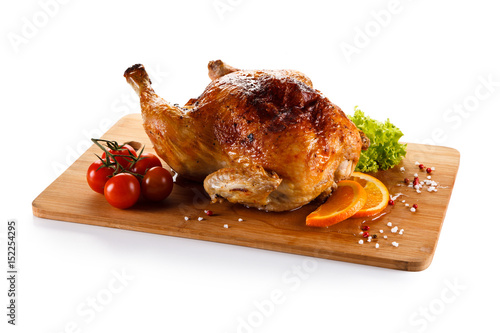 Roast chicken on cutting board on white background