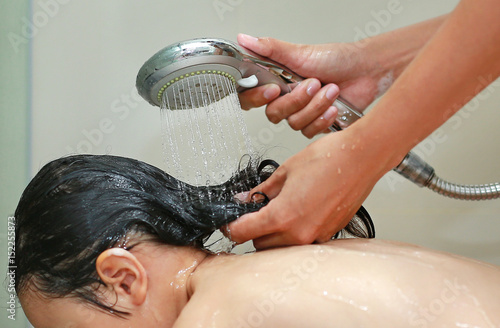 Little girl bathing and washing hair in bubble bath.