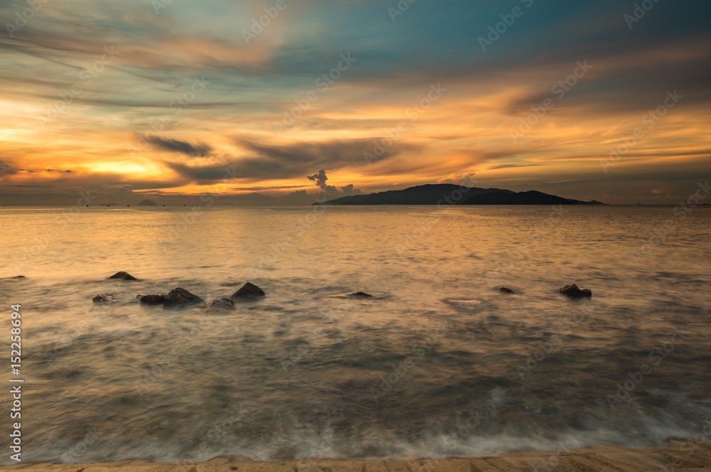 Vietnam Nha Trang bay at sunrise with a beautiful colourful sky over the south china sea with rocks in the foreground.
