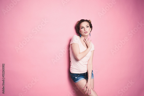 close-up portrait of young beautiful slim sexy young blonde woman in a retro pin-up style on pink background in studio wearing sunglasses smiling and posing © bublik_polina