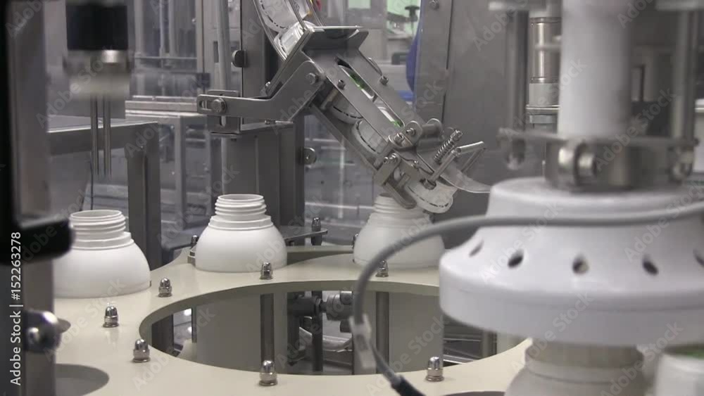 Line at the Enterprise for Dividing Liquids into White Plastic Bottles. Industry Machine Bottling Liquid. Bottling Line on Plant Line at the Enterprise for Dividing Liquids into White Plastic Bottles. Industry Machine Bottling Liquid. Bottling Line on Plant