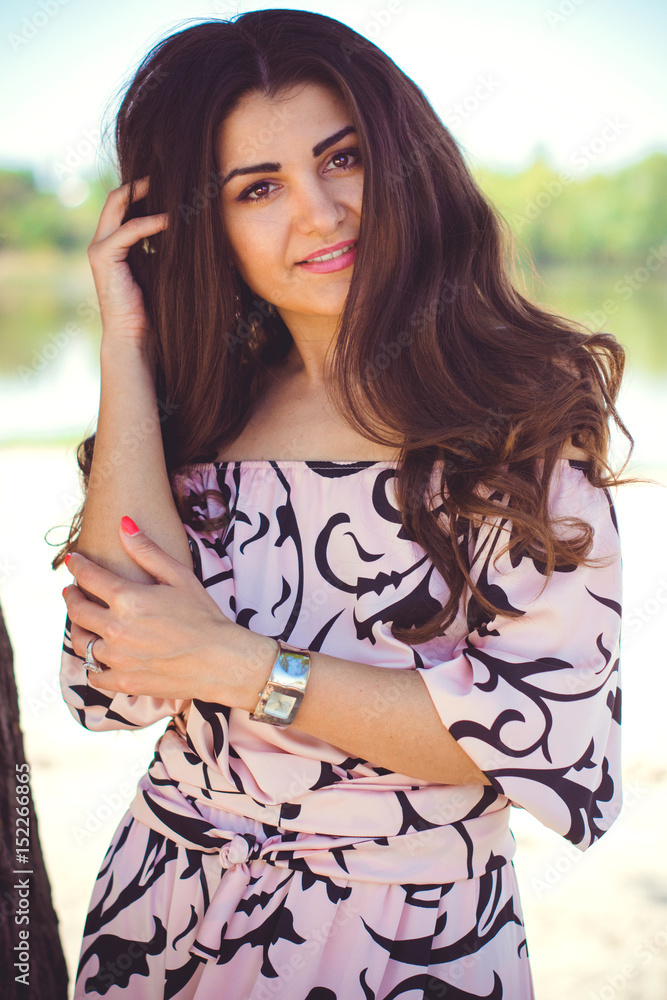 Beautiful spanish happy woman with long dark hair in long dress on vacation on a beach around water Beautiful spanish happy woman with long dark hair in long dress on vacation on a beach around water