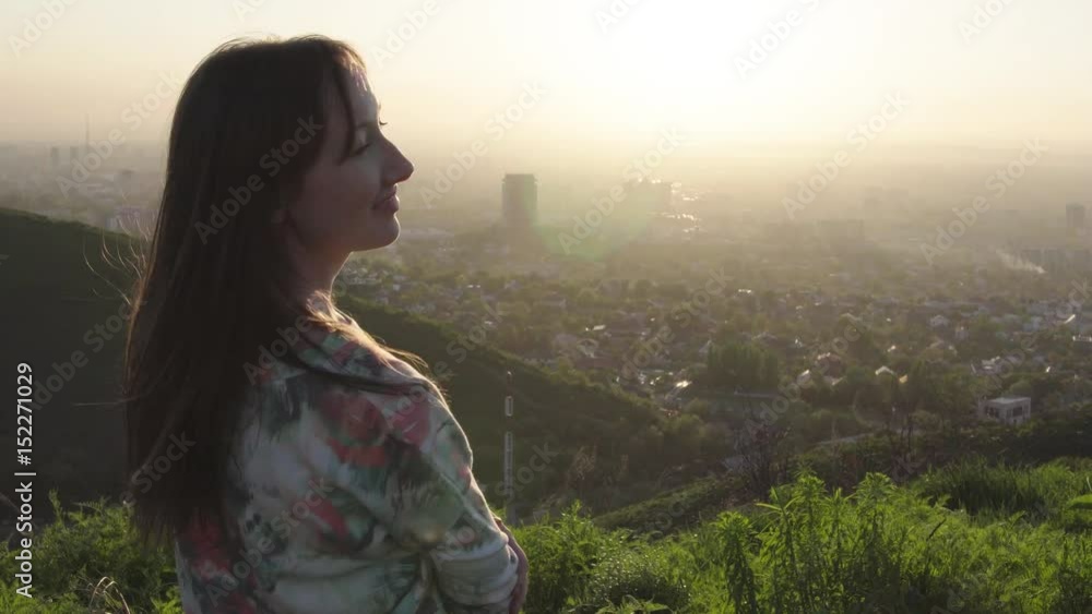 Close up portrait of beautiful young woman running hand through hair blowing in wind City top, Girl smile hair shows in the distance. Almaty. Close up portrait of beautiful young woman running hand through hair blowing in wind City top, Girl smile hair shows in the distance. Almaty.