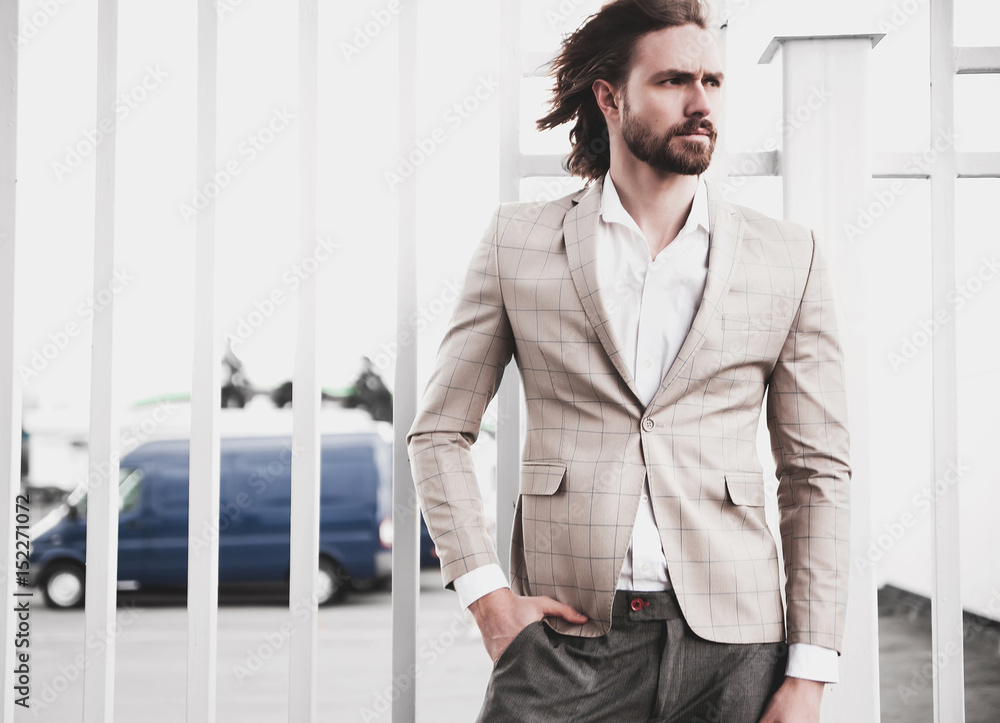 portrait of sexy handsome fashion male model man dressed in elegant beige checkered suit .posing on the street background portrait of sexy handsome fashion male model man dressed in elegant beige checkered suit .posing on the street background