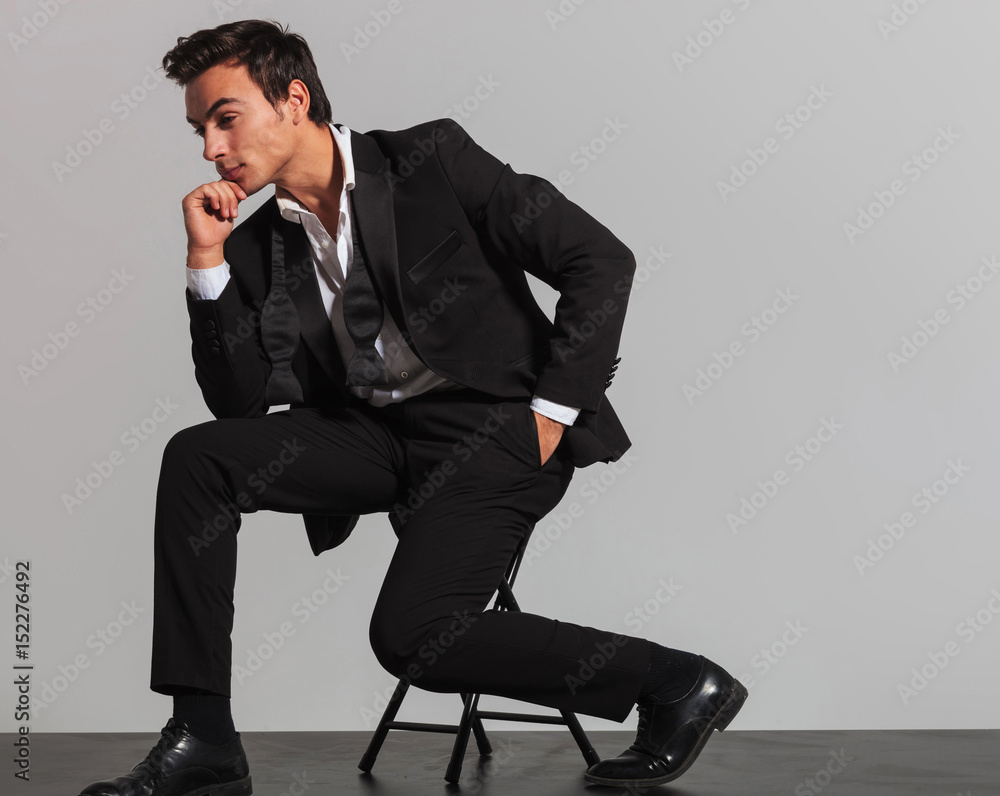 side view of a thoughtful elegant man sitting on chair side view of a thoughtful elegant man sitting on chair