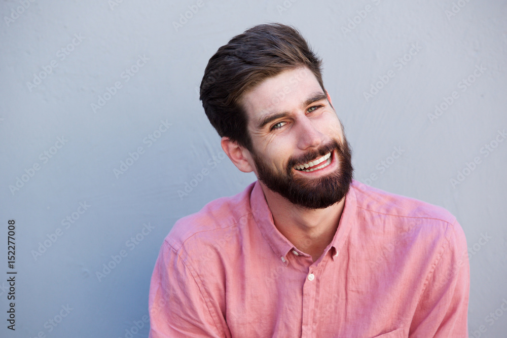 Fototapeta premium handsome man with beard laughing against gray wall