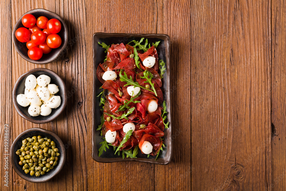 Beef carpaccio served with balls of mozzarella cheese, arugula and capers. Beef carpaccio served with balls of mozzarella cheese, arugula and capers.