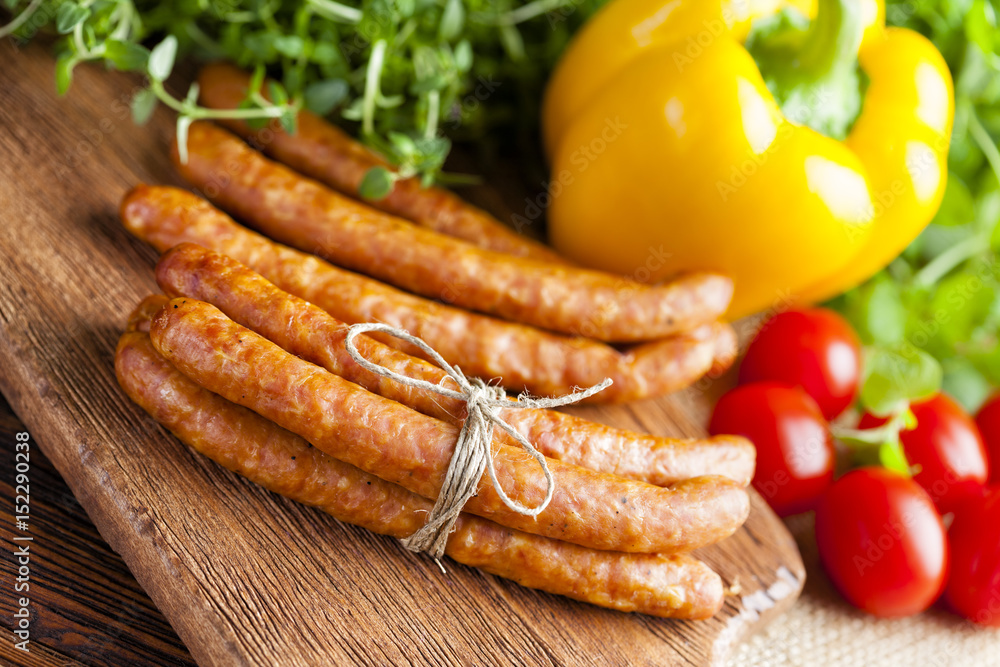Sausage, herbs and vegetables on wooden and canvas background