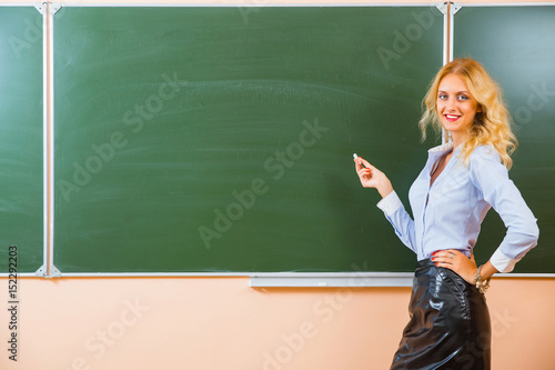 Beautiful young sexy teacher standing near the blackboard