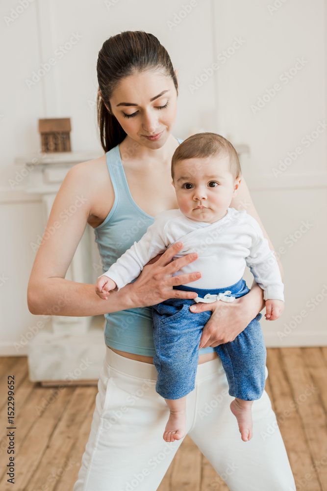 Portrait of woman carrying baby child on arms at home Portrait of woman carrying baby child on arms at home