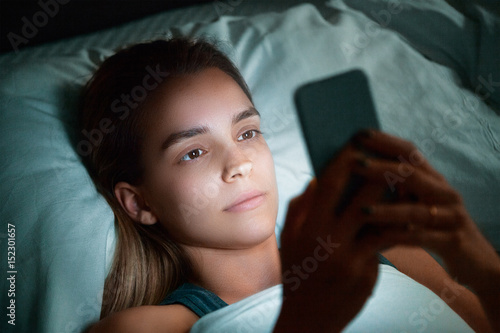Donna a letto con cellulare, invia messaggi