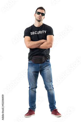 Macho bouncer or undercover cop in plain clothes looking at camera with crossed arms. Full body length portrait isolated on white studio background.  photo