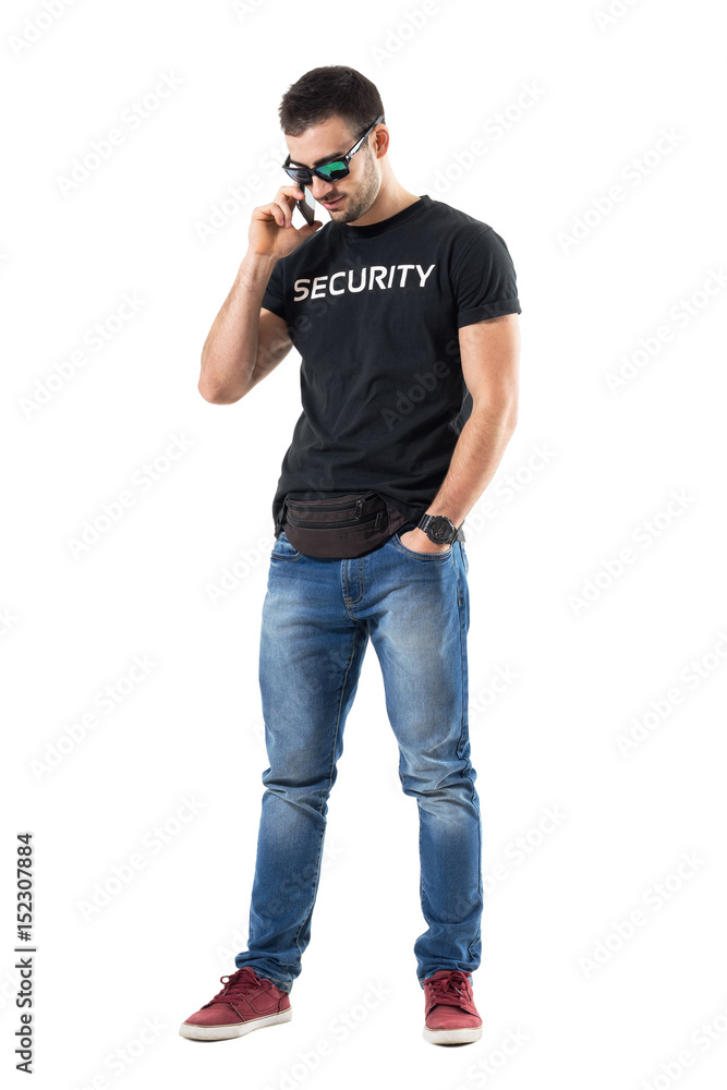 Smiling happy relaxed undercover policeman talking on the phone looking down. Full body length portrait isolated on white studio background. Smiling happy relaxed undercover policeman talking on the phone looking down. Full body length portrait isolated on white studio background.