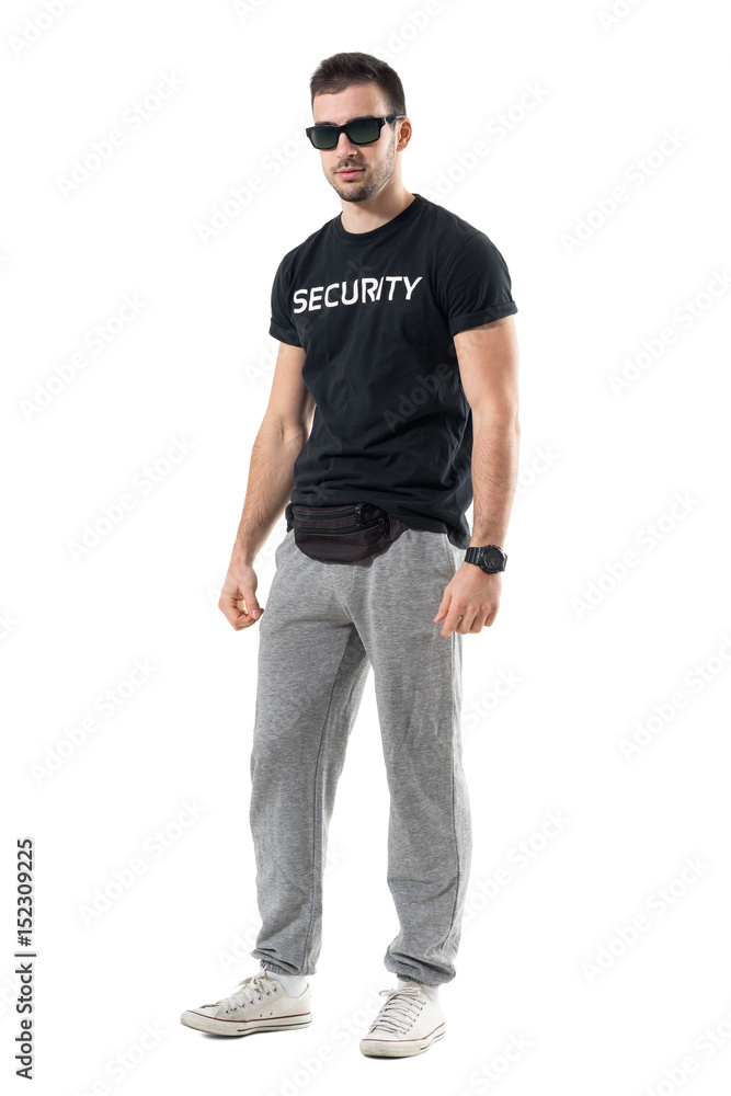 Young police officer in plain sporty clothes with sunglasses looking at camera. Full body length portrait isolated on white studio background. Young police officer in plain sporty clothes with sunglasses looking at camera. Full body length portrait isolated on white studio background.