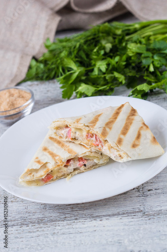 shawarma in thin pita bread with chicken and vegetables on a plate