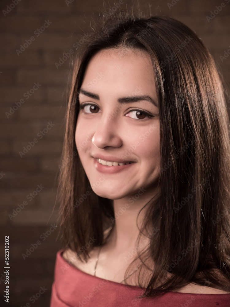 Splendid slender girl stands and smiles in a red brick studio Splendid slender girl stands and smiles in a red brick studio