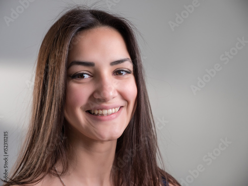Attractive young woman with happy eyes stands and smiles in studio