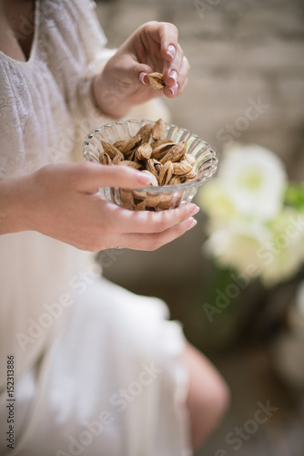 Beautiful pregnant girl with black hair in a vintage chair holding a glass plate with almonds