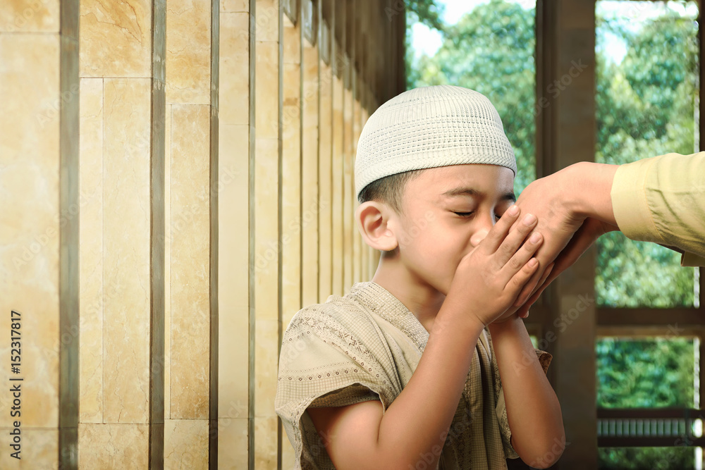 Asian muslim kid kissing his parent hand as respect symbol