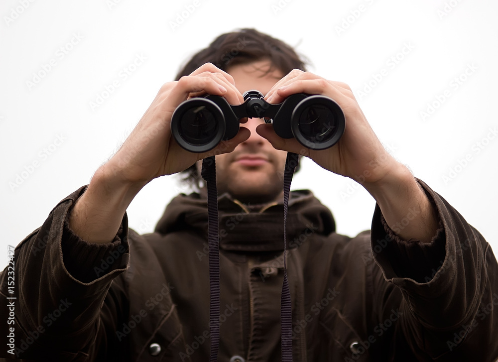 Man looking through the binoculars against mist background Man looking through the binoculars against mist background