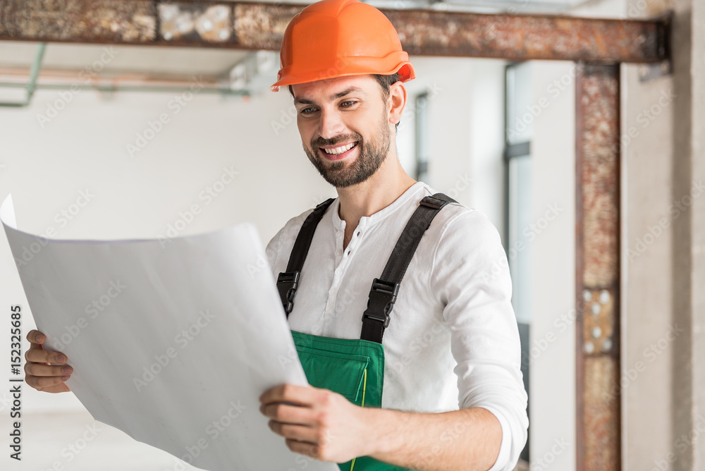 Interested smiling constructor keeping paper Interested smiling constructor keeping paper