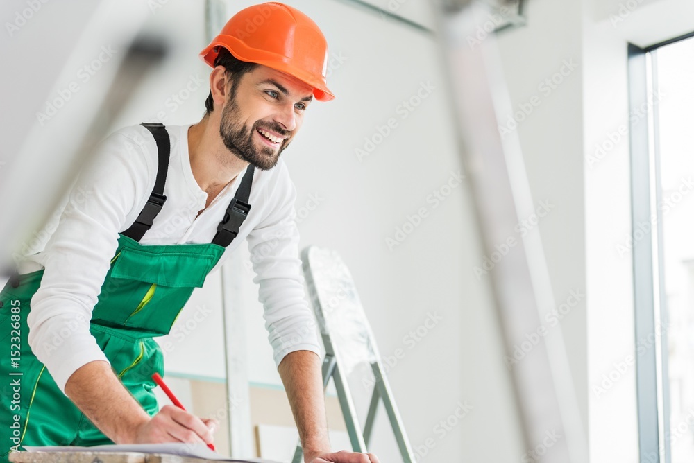 Cheerful smiling builder keeping pen Cheerful smiling builder keeping pen
