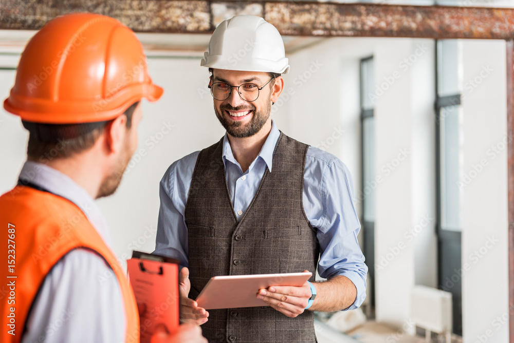 Hilarious smiling foreman talking to coworker Hilarious smiling foreman talking to coworker