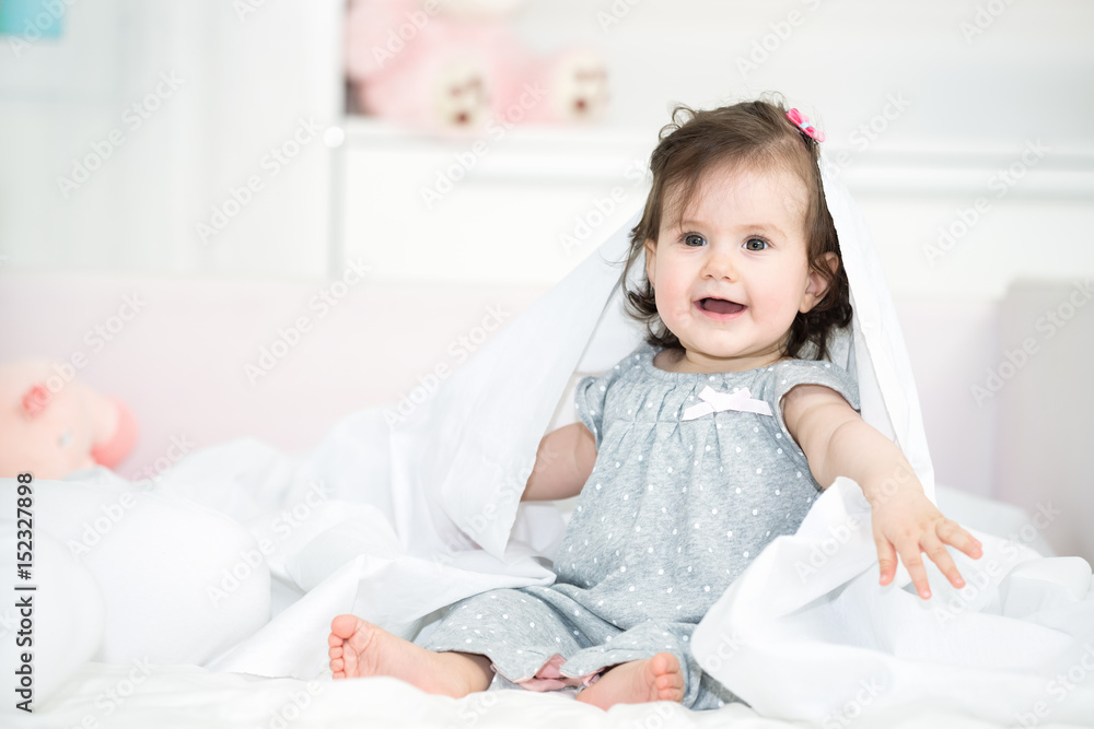 Sweet baby girl playing with a bed sheet in the bed. Shallow doff Sweet baby girl playing with a bed sheet in the bed. Shallow doff