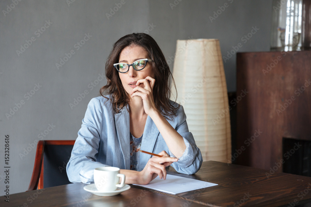 Thoughtful woman writer sitting indoors Thoughtful woman writer sitting indoors