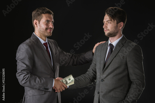 Canvastavla Businessmen shaking hands with dollar banknotes isolated on black