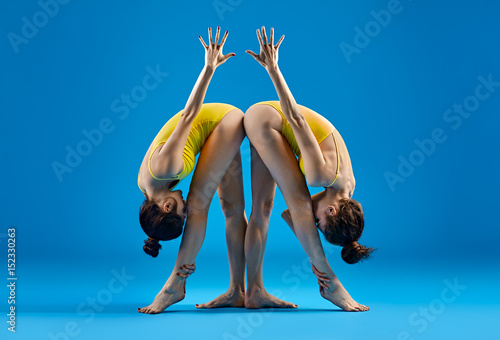 Two young women doing yoga asana standing Parsvottanasana photo