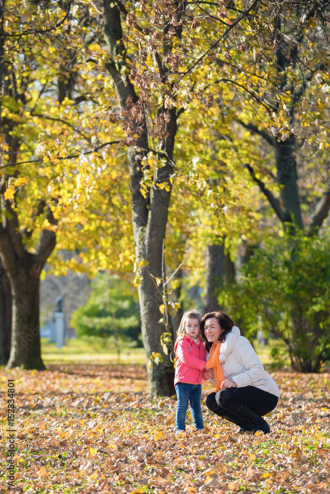 Mother and daughter together looking away in autumn park