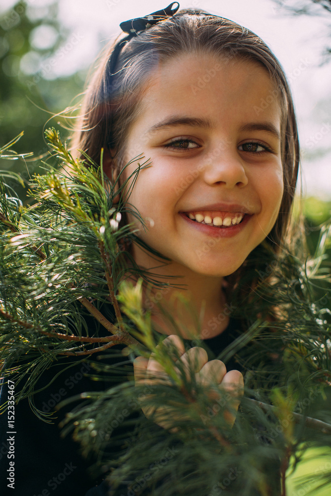 Girl smiling and holding pine tree branch Girl smiling and holding pine tree branch