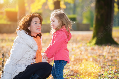Mother and daughter talking in the autumn park. Lens flare.