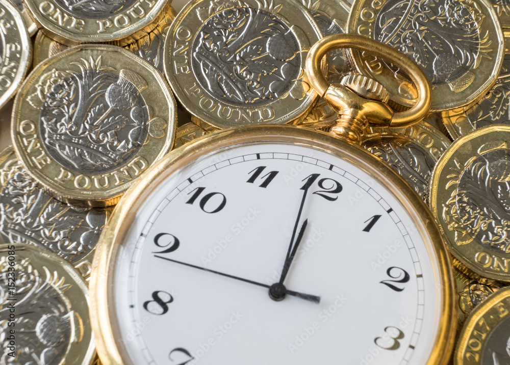Time and money, gold watch on a pile of UK coins