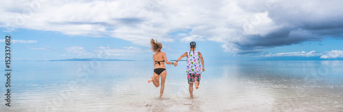Couple running towards the sky on a sandbar