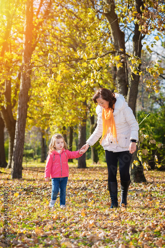 Mother and daughter walking through the autumn park.Lens flare.Focus on the daughter face