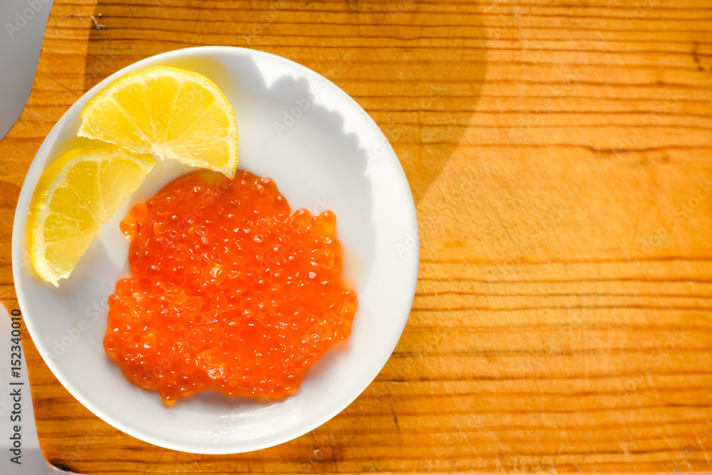 Closeup on person eating red caviar delicacy from white plate, closeup light macro background Closeup on person eating red caviar delicacy from white plate, closeup light macro background