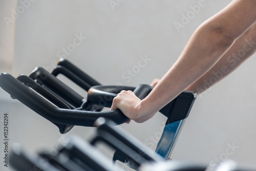 Female sportsman trains on a stationary bike. A female fitness instructor doing exercises. Fitness club gym training lifestyle commercial concept.
