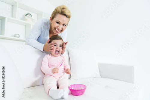 Baby little girl making a funny screaming face while mom behind her touching her face. Shallow doff, copy space