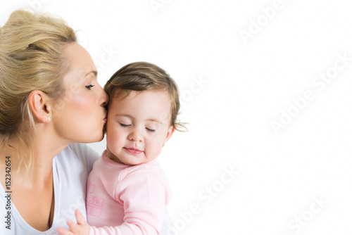 Portrait of hugging mom and baby little girl, mom kissing her daughter while baby eyes closed.Copy space, white background, isolated on white