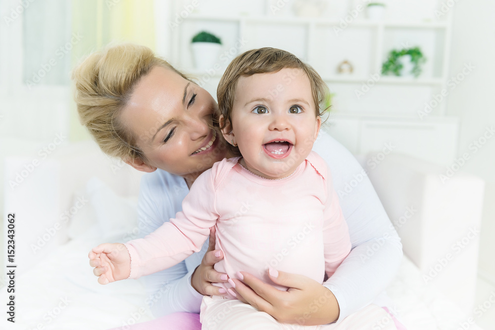 Smiling baby little girl in mom's arms  looking at camera.Shallow doff