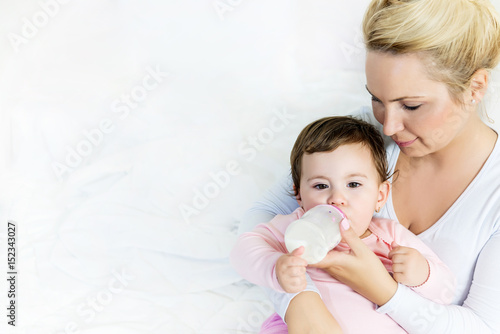 Baby little girl drinking a milk from bottle in the mom's arms.sleeping baby.Shallow doff, copy space
